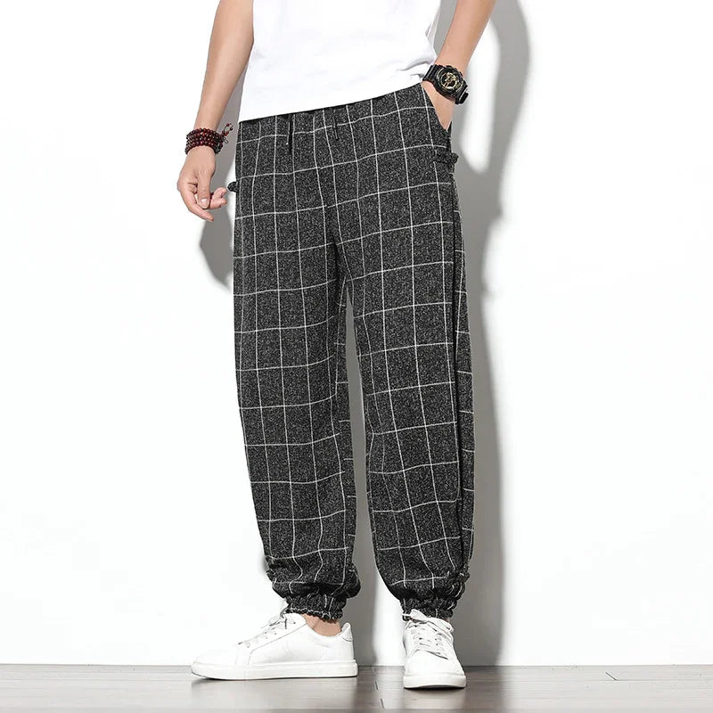 Men's casual black and white checkered jogger pants with elastic cuffs, paired with white sneakers
