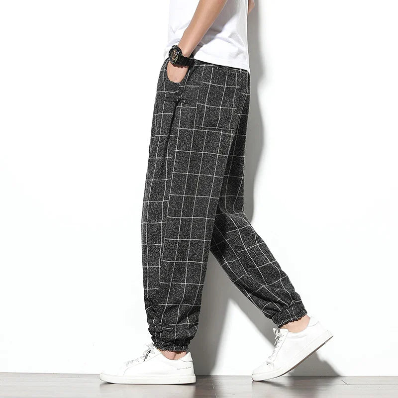 Person wearing black and white grid pattern casual pants with elastic cuffs and white sneakers