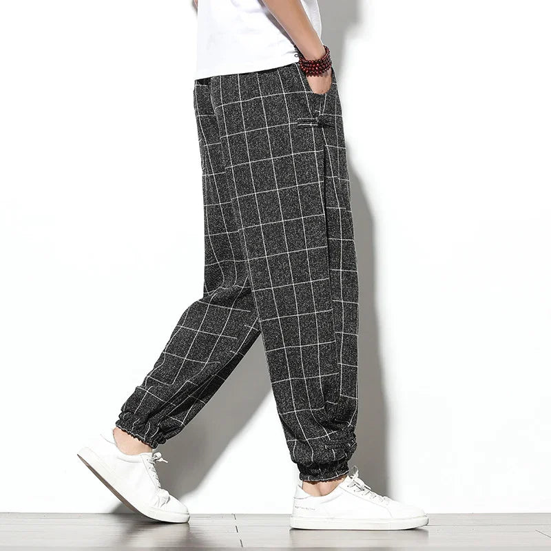 Side view of person wearing black and white checkered casual jogger pants with elastic cuffs and white sneakers