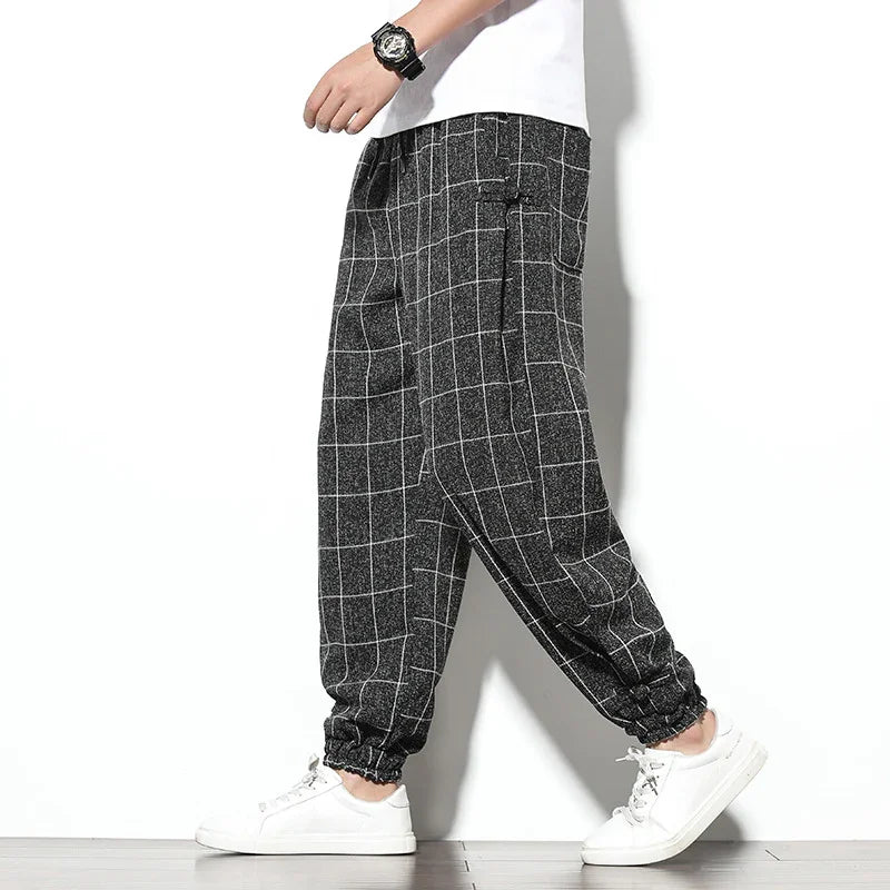 Men's black checkered jogger pants with white grid pattern, paired with white sneakers and a white t-shirt