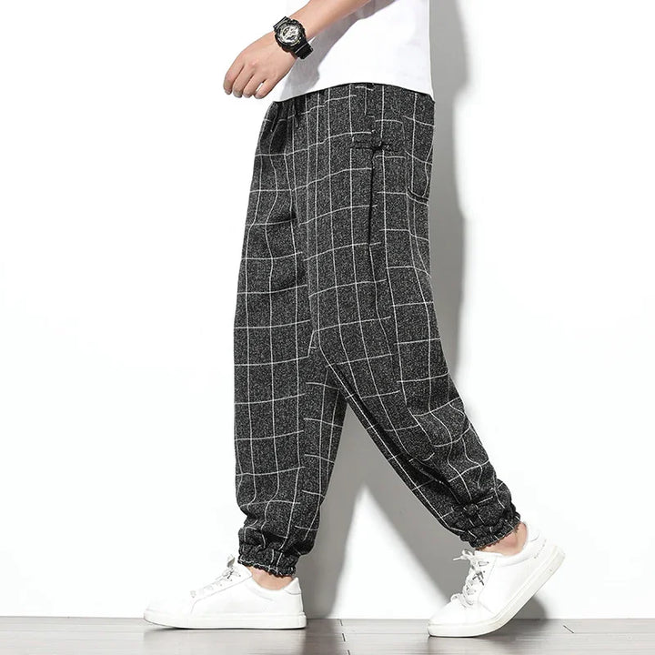 Men's black checkered jogger pants with white grid pattern, paired with white sneakers and a white t-shirt