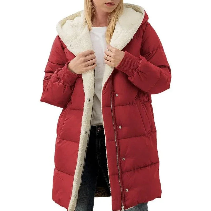 Woman wearing a long red puffer coat with white sherpa lining and hood, styled with jeans and a white top