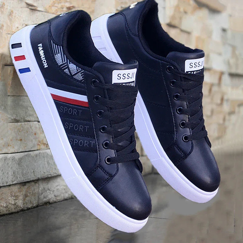 Black sport sneakers with white soles and red, white, blue stripes against a stone wall