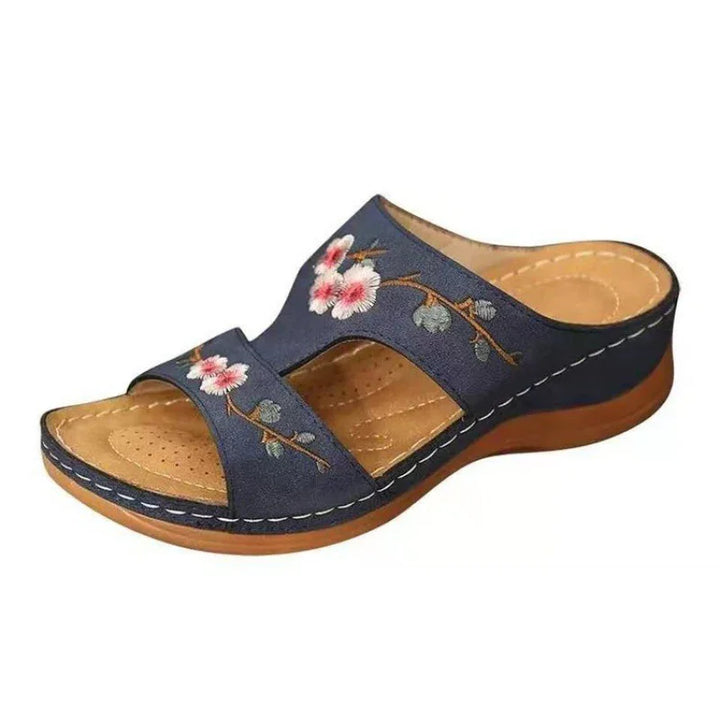 Women's navy blue open-toe sandal with floral embroidery and cushioned tan insole