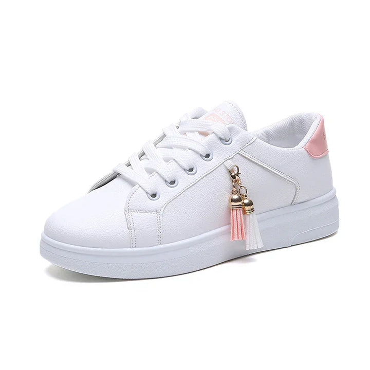 White casual sneaker with pink heel accent and decorative pink and white tassels