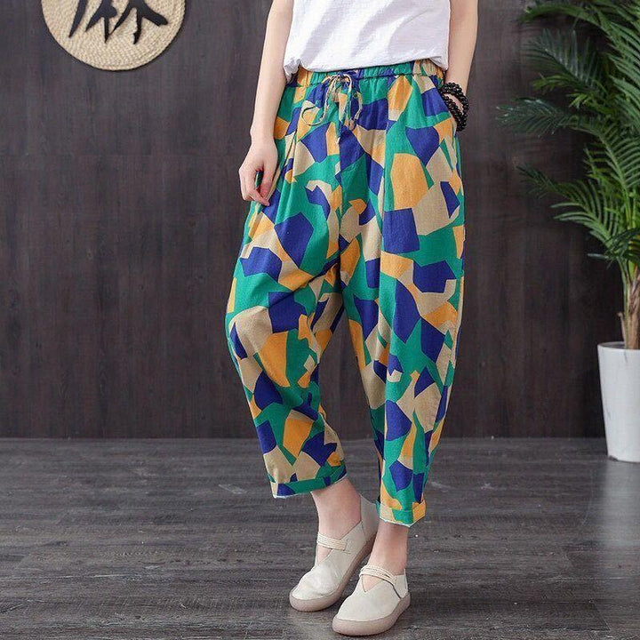 Person wearing colorful geometric print loose pants with white shoes standing on wooden floor