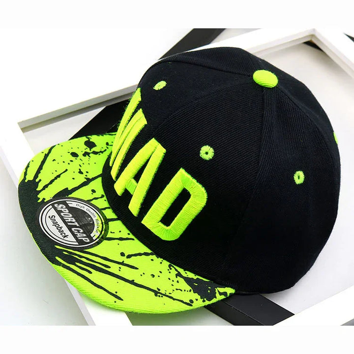 Black and neon green snapback cap with MAD embroidery and paint splatter brim design