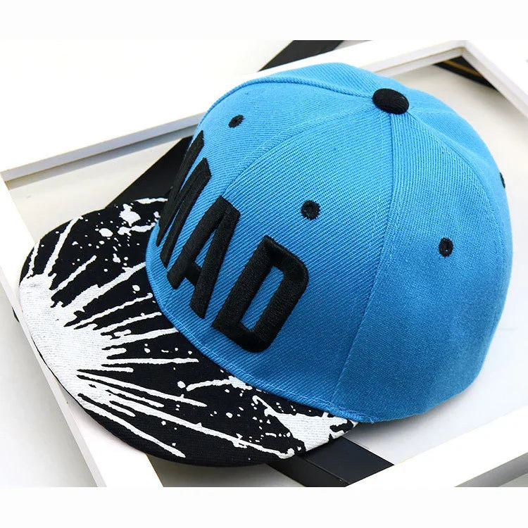 Blue snapback cap with black embroidered MAD text and black-white splash patterned brim