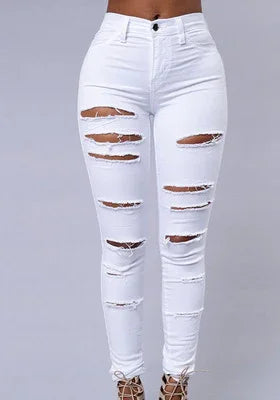 Woman wearing high-waisted white ripped skinny jeans with heels on grey background