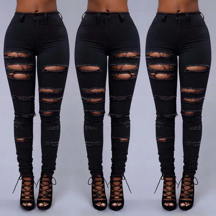 Front view of black distressed skinny jeans with multiple ripped details worn with black lace-up heels