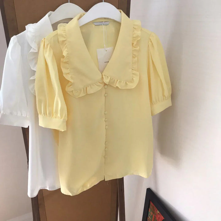 Yellow and white puff sleeve blouses with ruffled collars hanging on white hangers
