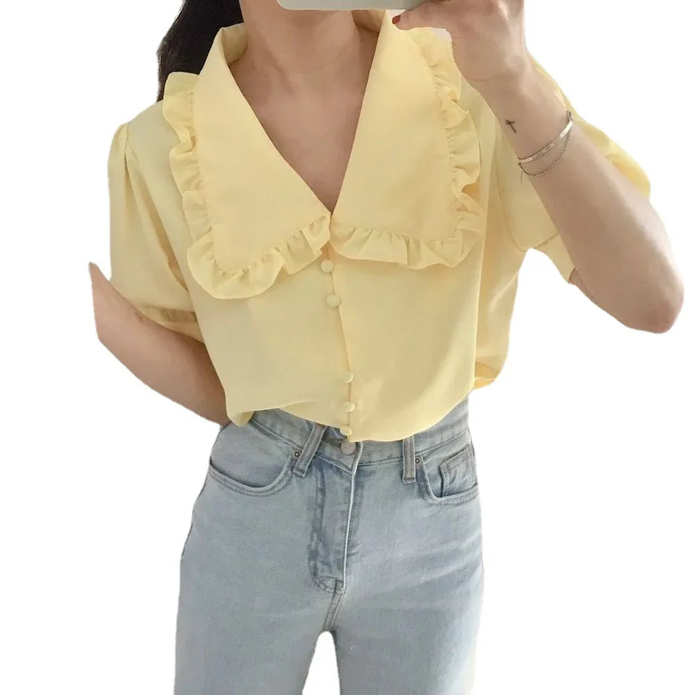 Woman wearing light yellow ruffle collar button-up blouse with light blue high-waisted jeans