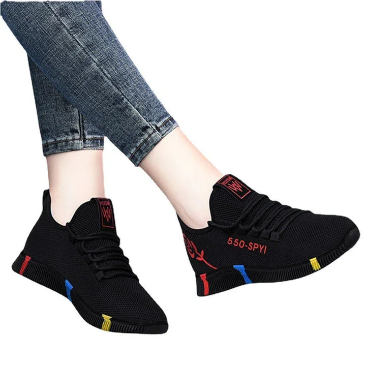 Black mesh sneakers with red '550-SPYI' text and multicolor sole accents worn with blue jeans