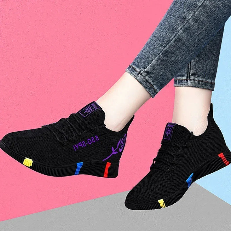 Black casual sneakers with colorful sole accents and purple rose details worn with rolled-up jeans on pink and blue background