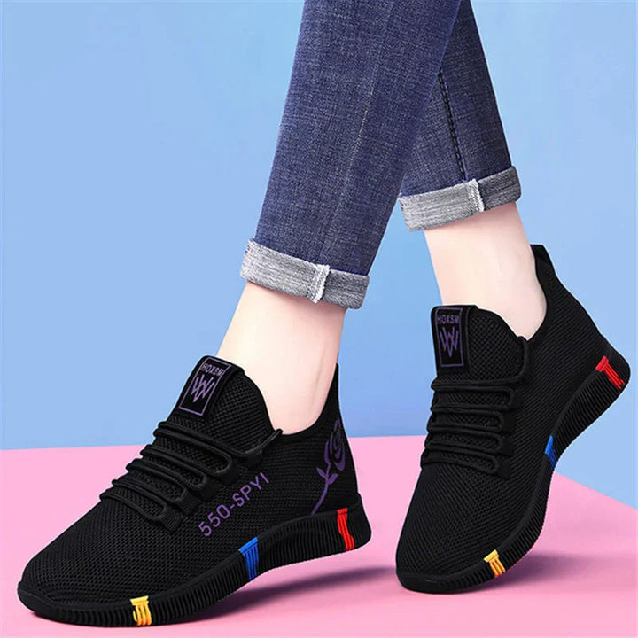 Black mesh sneakers with colorful sole accents and purple 550-SPYI text, worn with rolled-up blue jeans