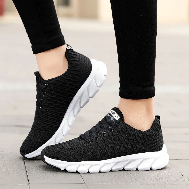 Black lightweight knit sneakers with thick white cushioned soles worn with black leggings