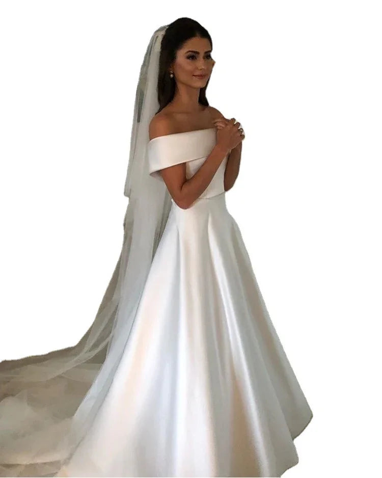 Bride wearing elegant off-shoulder white satin wedding gown with long veil