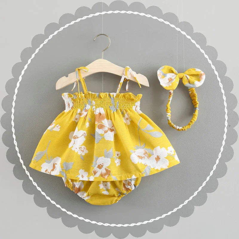 Yellow floral baby dress with matching headband on wooden hanger against gray background