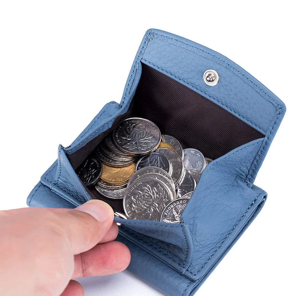 Hand holding open blue leather coin purse filled with assorted silver and gold coins