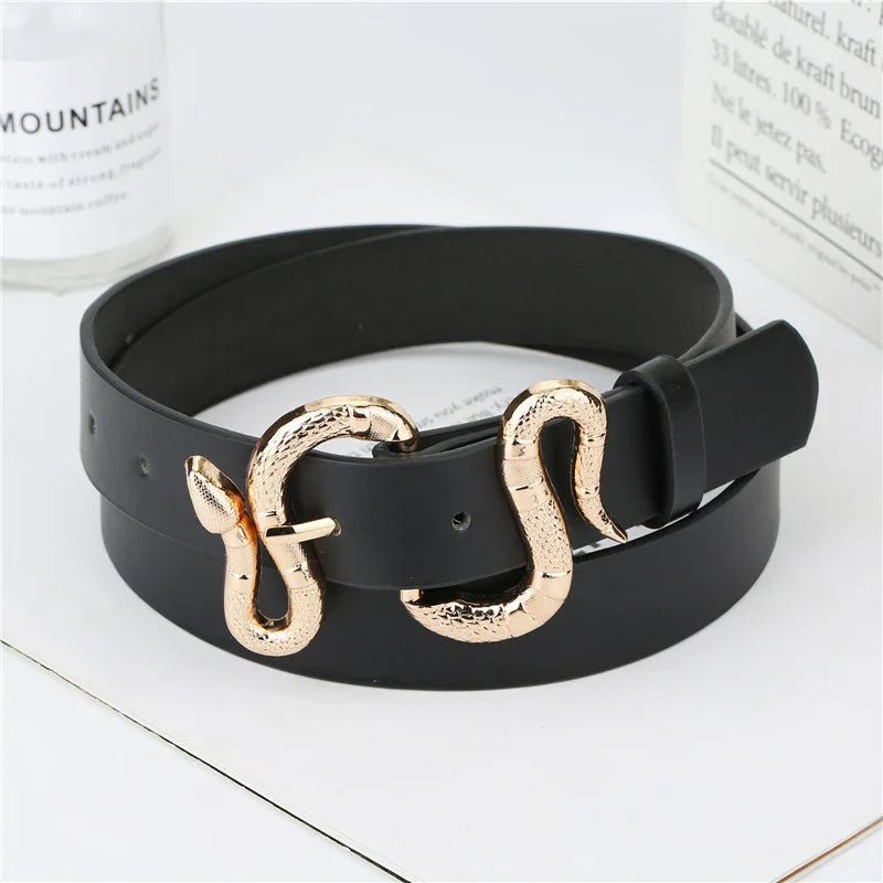 Black leather belt with gold snake-shaped buckle on white surface with books