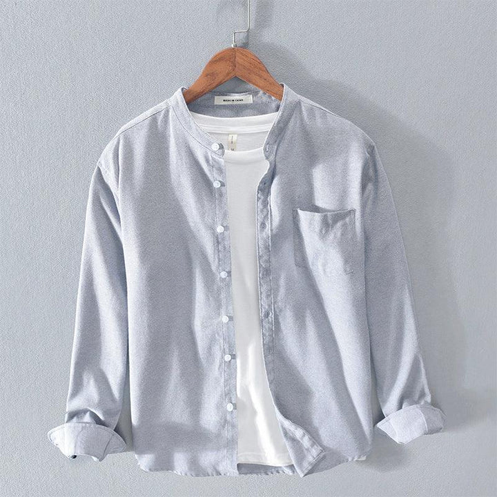 Light gray button-up shirt with mandarin collar over white t-shirt on wooden hanger