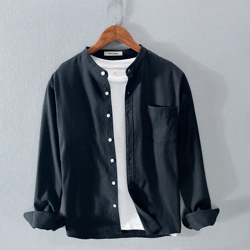Black button-up shirt with mandarin collar over white t-shirt on wooden hanger against grey background
