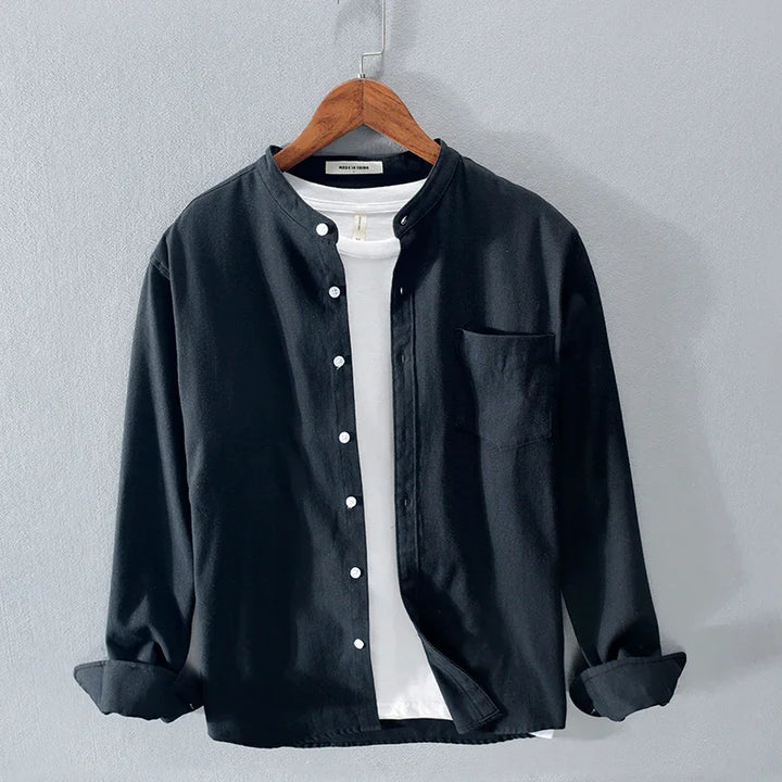 Black button-up shirt with mandarin collar over white t-shirt on wooden hanger against grey background