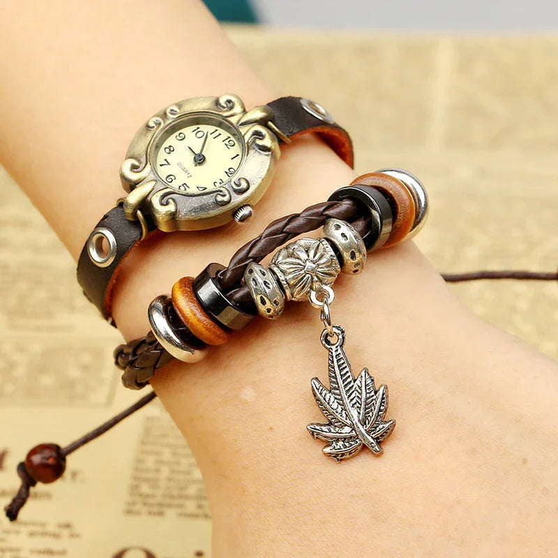Vintage-style wristwatch with leather strap and braided bracelet featuring silver leaf charm on wrist