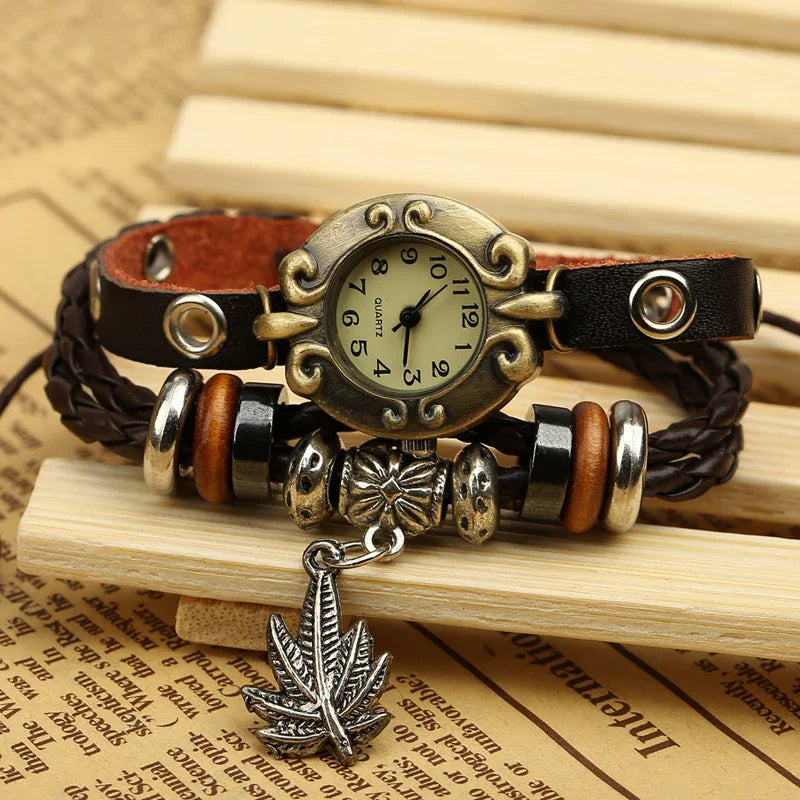 Vintage quartz watch with ornate bronze case, black braided leather strap, and leaf charm