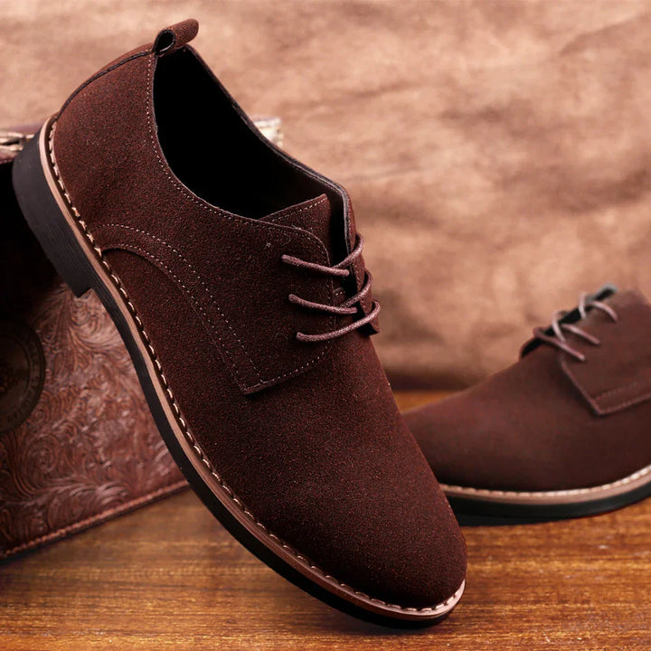 Brown suede men's casual lace-up shoes with stitched sole on wooden surface