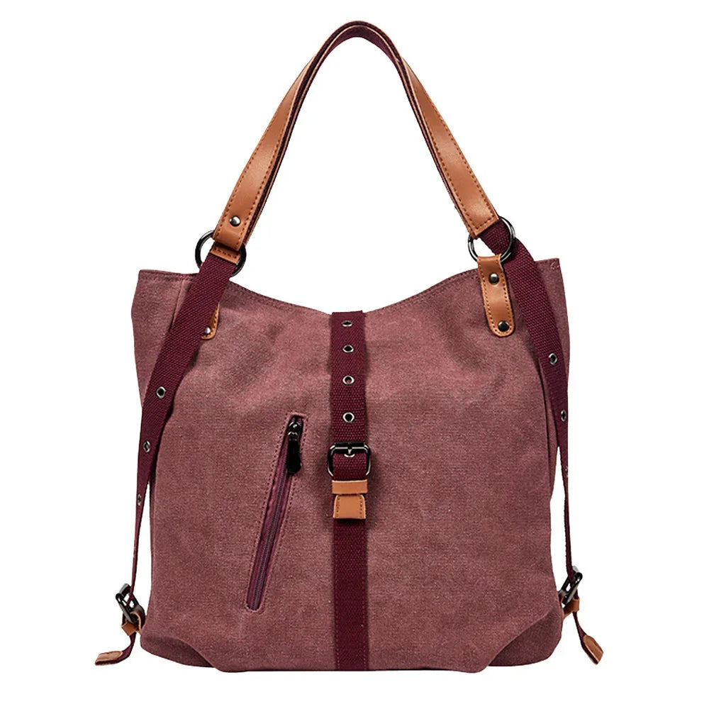 Mauve canvas tote bag with brown leather handles, adjustable shoulder strap, and front zipper pocket