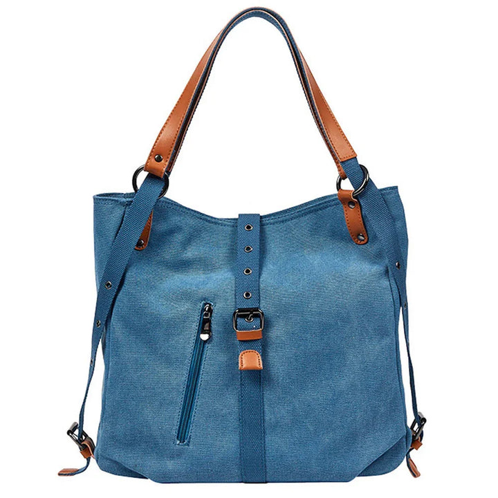 Blue canvas tote bag with brown leather handles and front zipper pocket