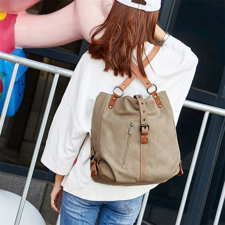 Woman wearing casual white top and jeans with beige canvas backpack featuring leather straps outdoors