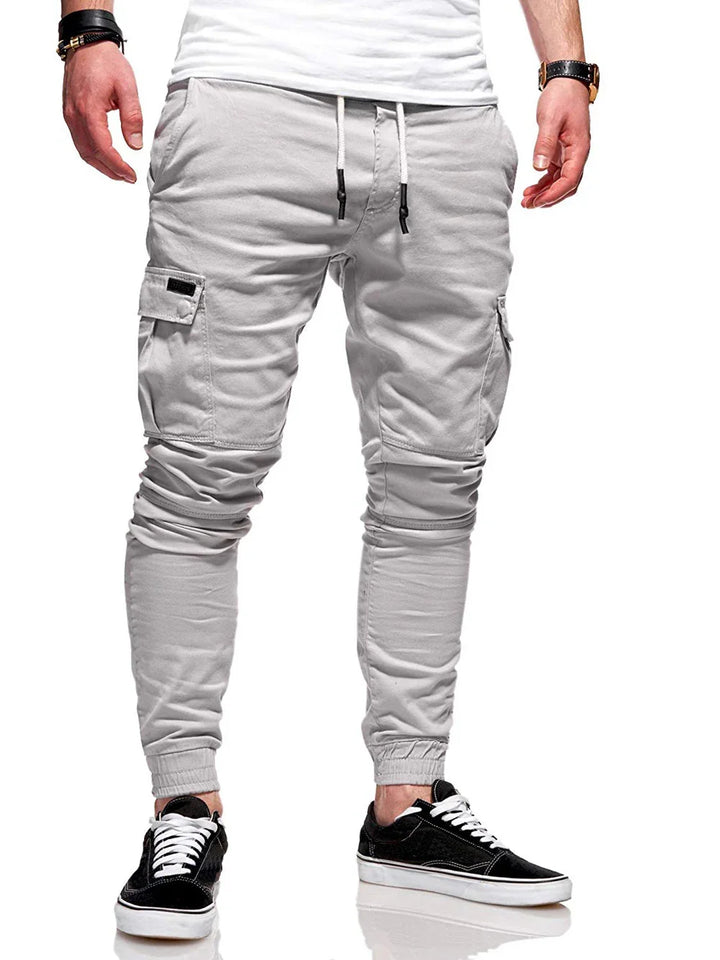 Man wearing light gray jogger cargo pants with drawstring waist and black casual sneakers