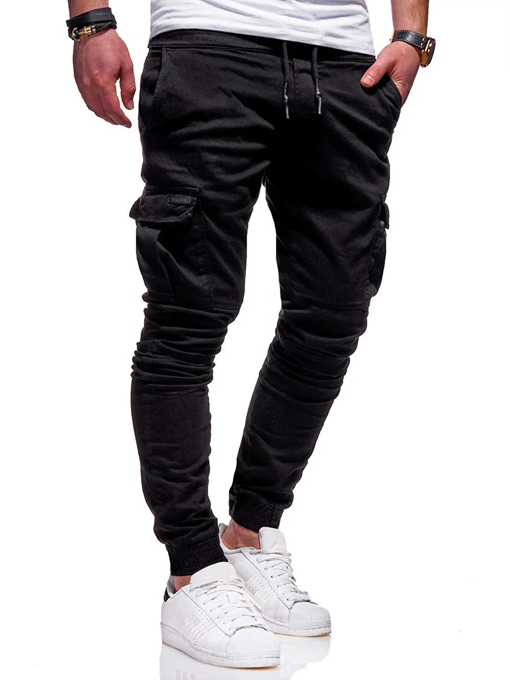 Man wearing black cargo jogger pants with drawstring waist and white sneakers against white background