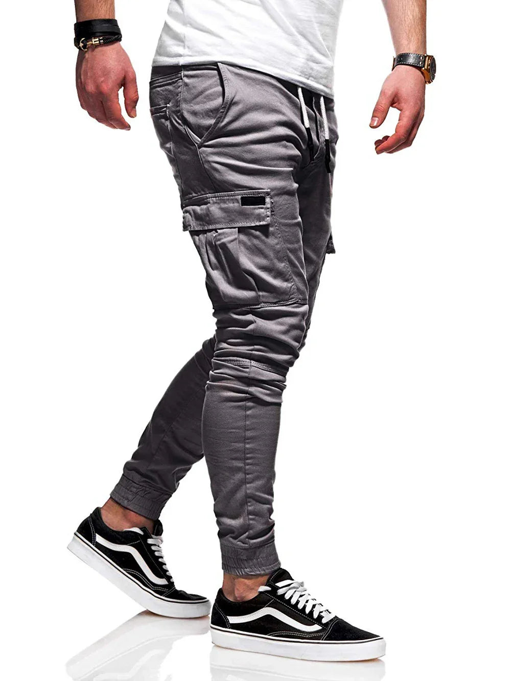 Man wearing grey cargo jogger pants with side pockets and black white sneakers on white background