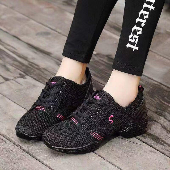 black mesh athletic sneakers with pink accents worn with black leggings on wooden floor