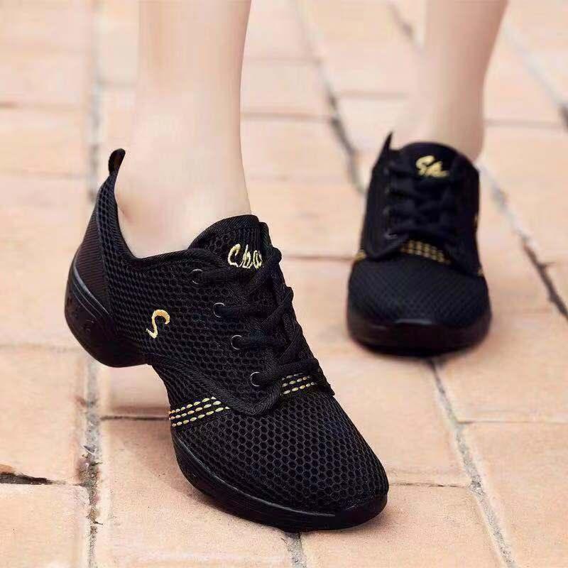 Black mesh breathable sneakers with gold stitching on tiled pavement