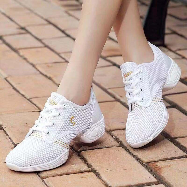 White breathable mesh dance sneakers with low heels worn on paved outdoor surface