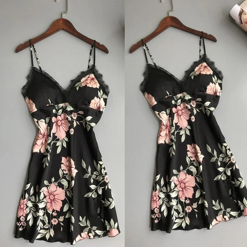 Black floral slip dress with pink flowers and lace trim on wooden hanger against gray background