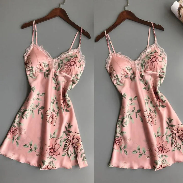 Pink floral satin slip dress with lace trim and spaghetti straps on wooden hanger