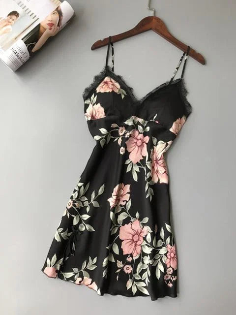 Black floral slip dress with pink flowers and lace trim on wooden hanger against gray background