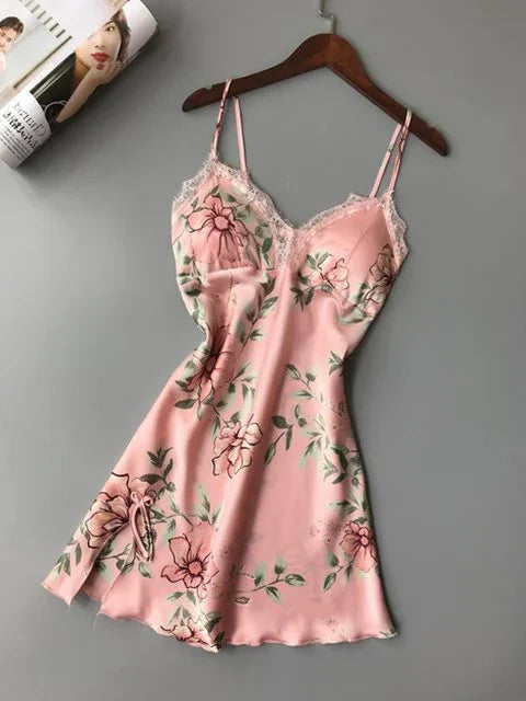 Pink floral satin slip dress with lace trim and adjustable straps on wooden hanger