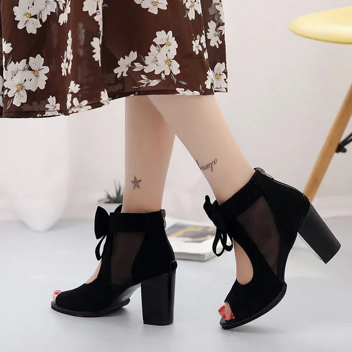Black mesh and suede high heel ankle boots with front bow detail, worn with floral dress