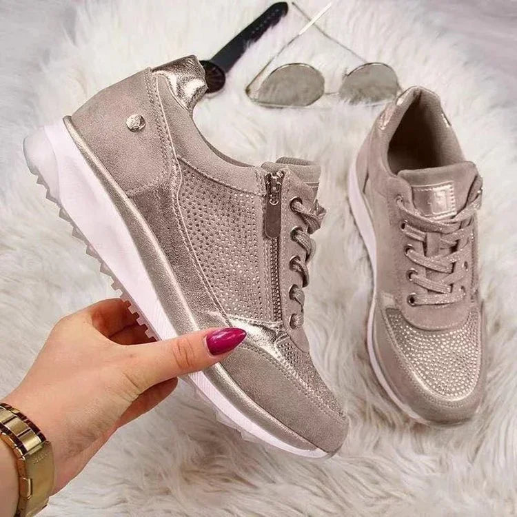 Metallic beige women's sneakers with zipper detail and white sole on white fur background