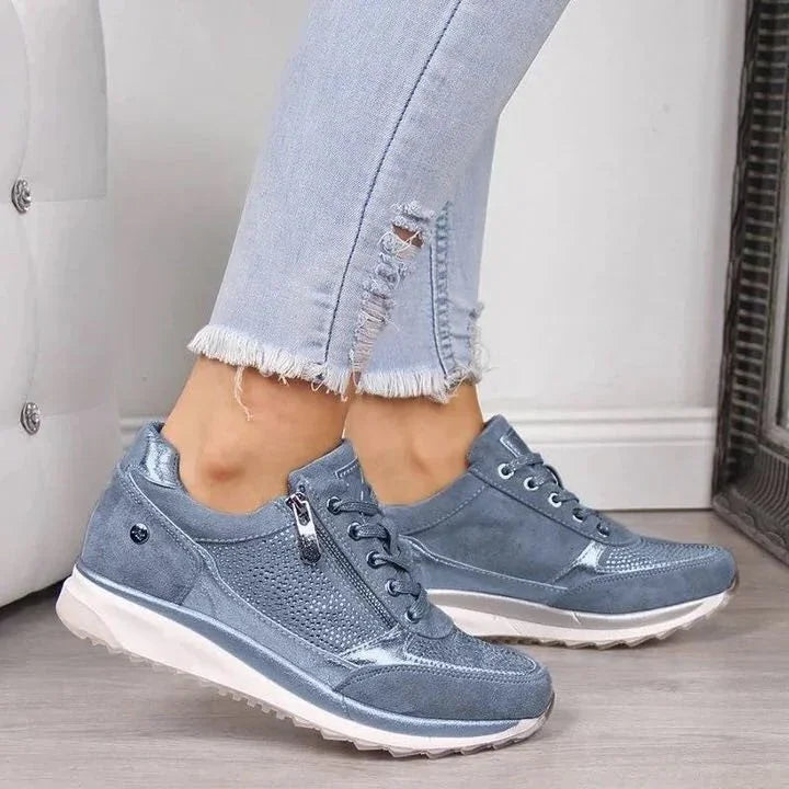 Blue suede and mesh casual sneakers with side zipper worn with light ripped skinny jeans indoors