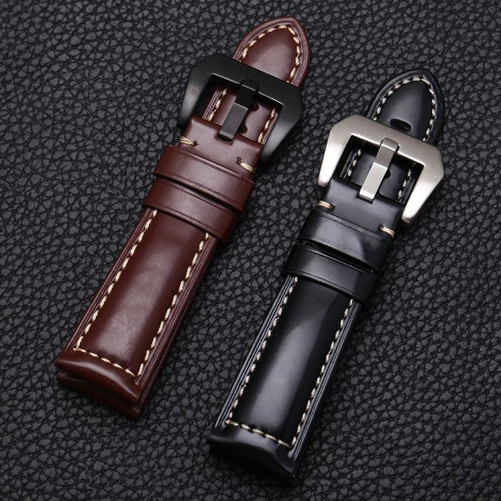 Two stitched leather watch straps in brown and black with large metal buckles on textured black surface