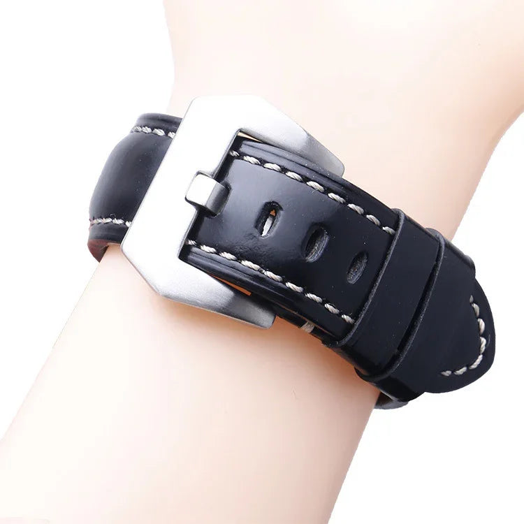 Black leather watch strap with white stitching and silver buckle on wrist