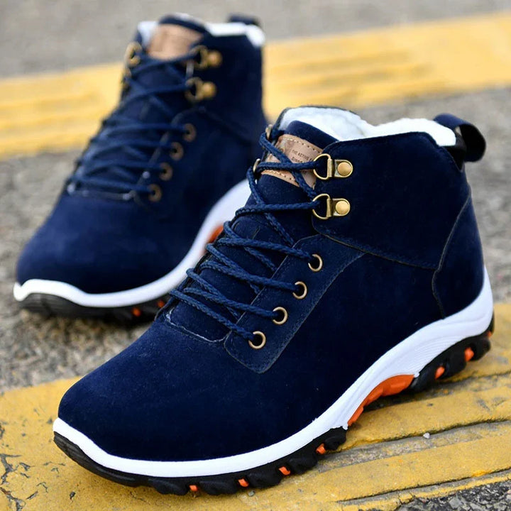 Navy blue high-top hiking boots with white soles and orange accents on pavement