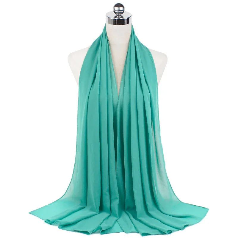 Light teal chiffon scarf draped on white mannequin with silver top against white background